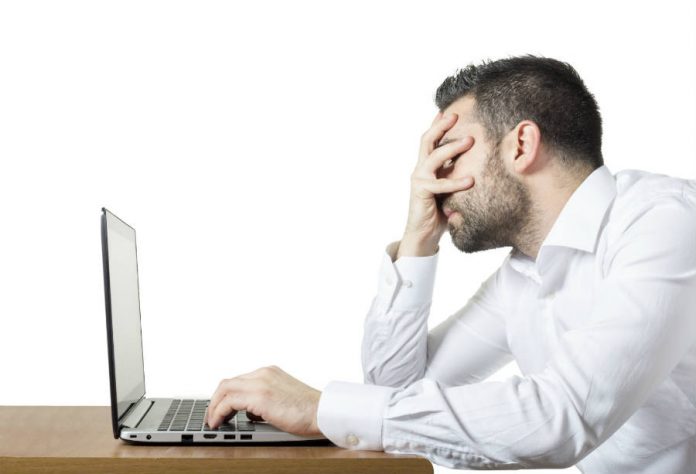 Frustrated man in front of a laptop.